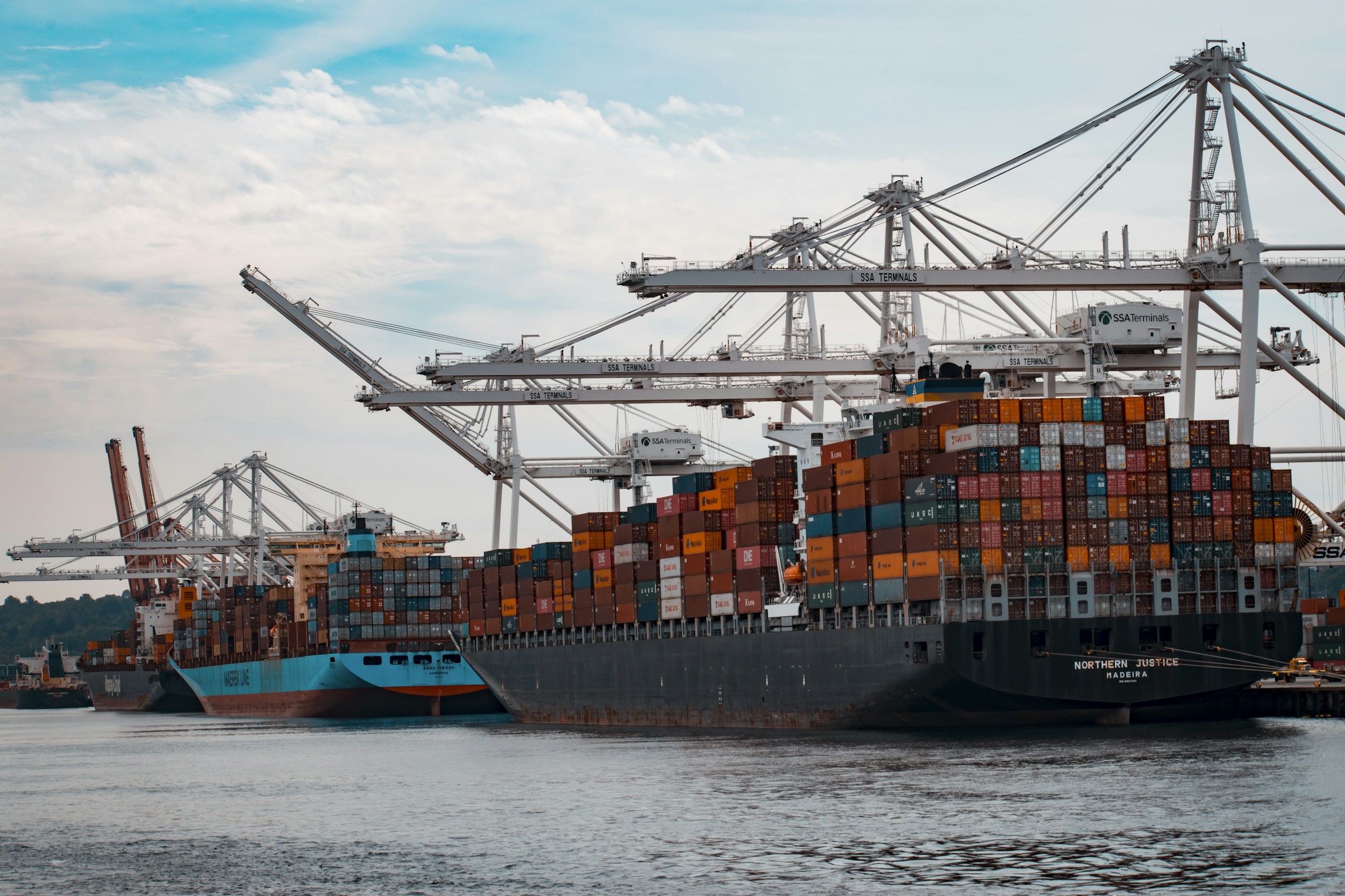 Container ship alongside commercial port cranes